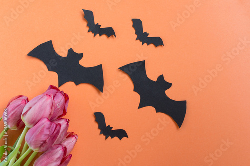 Black bats on an orange background with a bouquet of tulips. Halloween Holiday