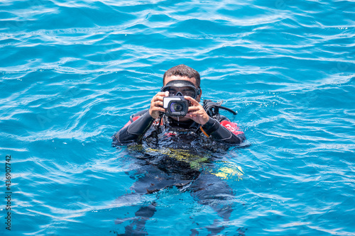 Underwater photographer videographer scuba dives on surface of sea. underwater photography and videography concept