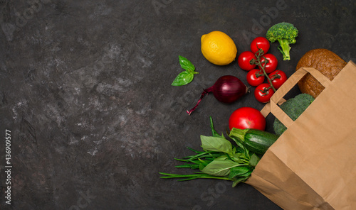 Healthy food background. Vegetables in paper bag on black background with copy space. Shopping food supermarket or food delivery concept.