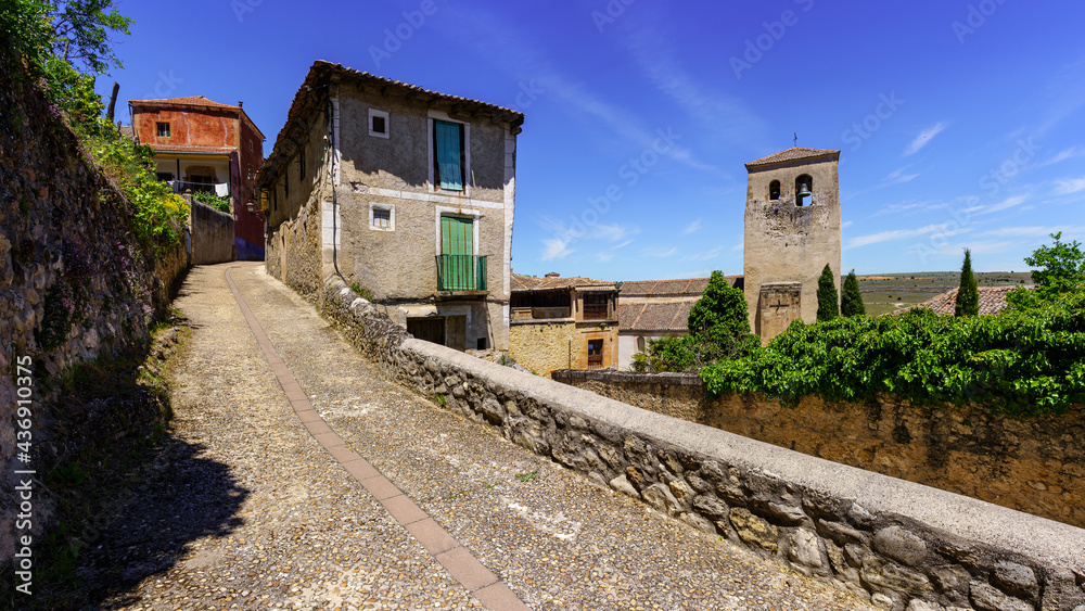 Panoramic of narrow street of old town with stone houses and church tower.