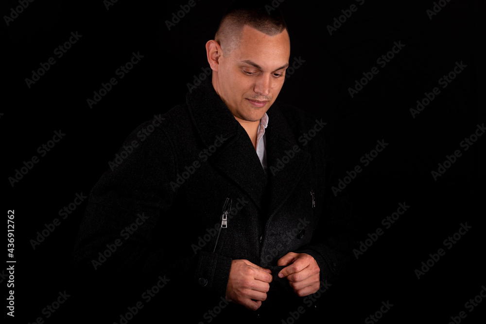 a young handsome man wears a black coat on a black background