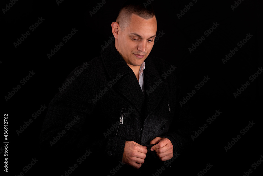 Fototapeta premium a young handsome man wears a black coat on a black background