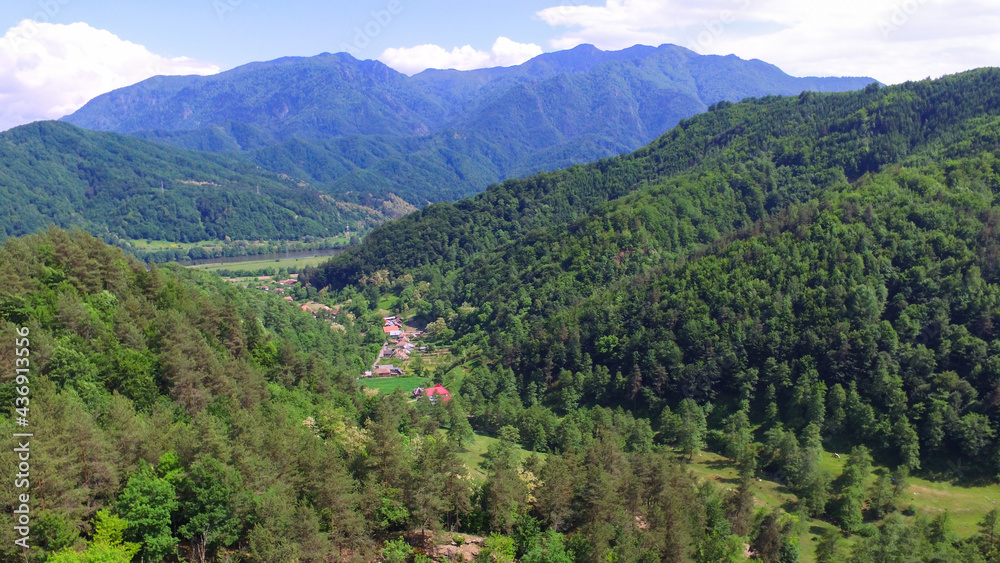 Obraz premium Aerial drone flying above Calinesti valley in Cozia Mountains. Calinesti village can be seen in the background, at the feet of Cozia Massif's rocky crests. Carpathia, Romania.