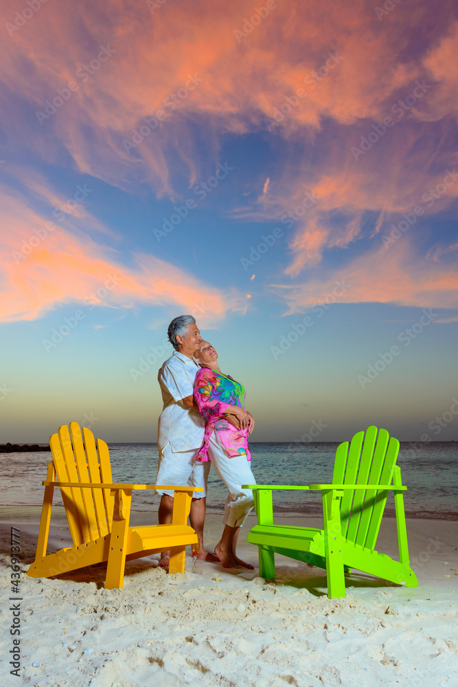 Romantic older couple at the beach hugging with beach chairs at sunset