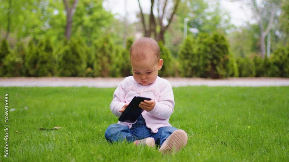 Baby girl concentrating on her phone at the park. Babies and technology. Baby girl concentrating on her phone at the park. Babies and technology.