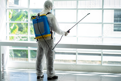 Asian social medical worker in PPE protective suit using disinfection spray to protect virus pandemic. 