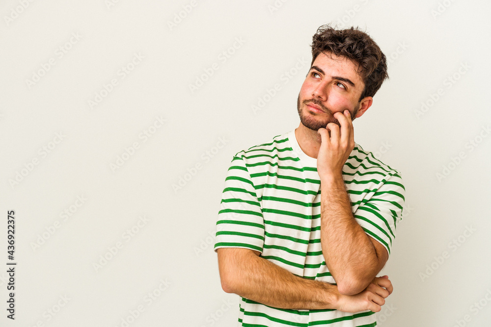 Young caucasian man isolated on white background relaxed thinking about something looking at a copy space.
