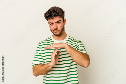 Young caucasian man isolated on white background showing a timeout gesture.