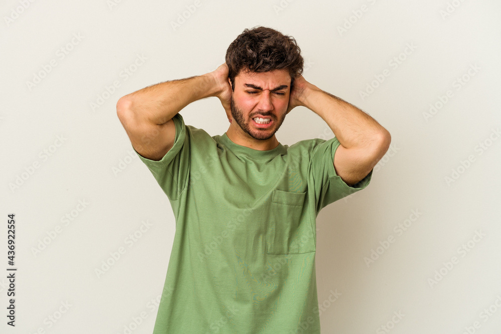 Young caucasian man isolated on white background covering ears with hands. Young caucasian man isolated on white background covering ears with hands.