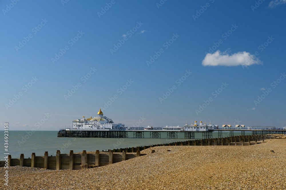 Empty shingle beach in Eastbourne on a summer's day with pier in the background