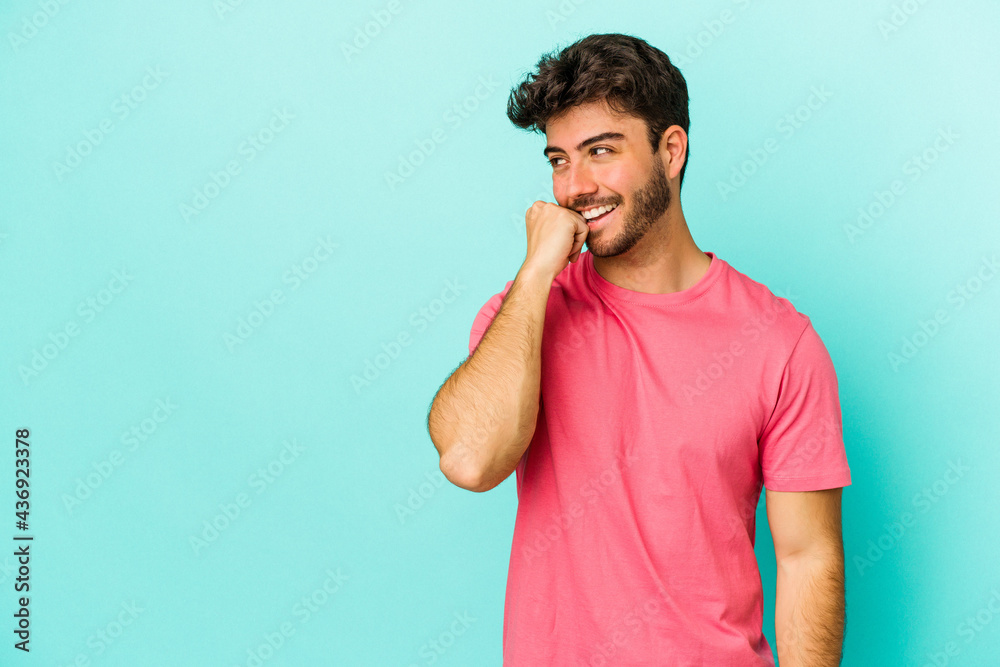 Young caucasian man isolated on blue background relaxed thinking about something looking at a copy space. Young caucasian man isolated on blue background relaxed thinking about something looking at a copy space.