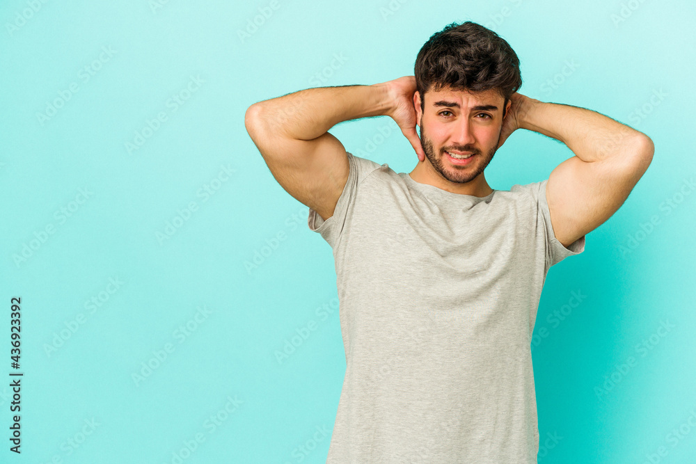 Young caucasian man isolated on blue background touching back of head, thinking and making a choice. Young caucasian man isolated on blue background touching back of head, thinking and making a choice.