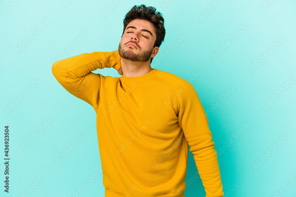 Young caucasian man isolated on blue background having a neck pain due to stress, massaging and touching it with hand. Young caucasian man isolated on blue background having a neck pain due to stress, massaging and touching it with hand.