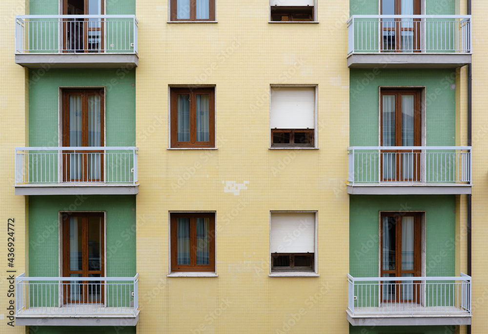 Fragment of yellow and green tiled facade building with balconies Fragment of yellow and green tiled facade building with balconies