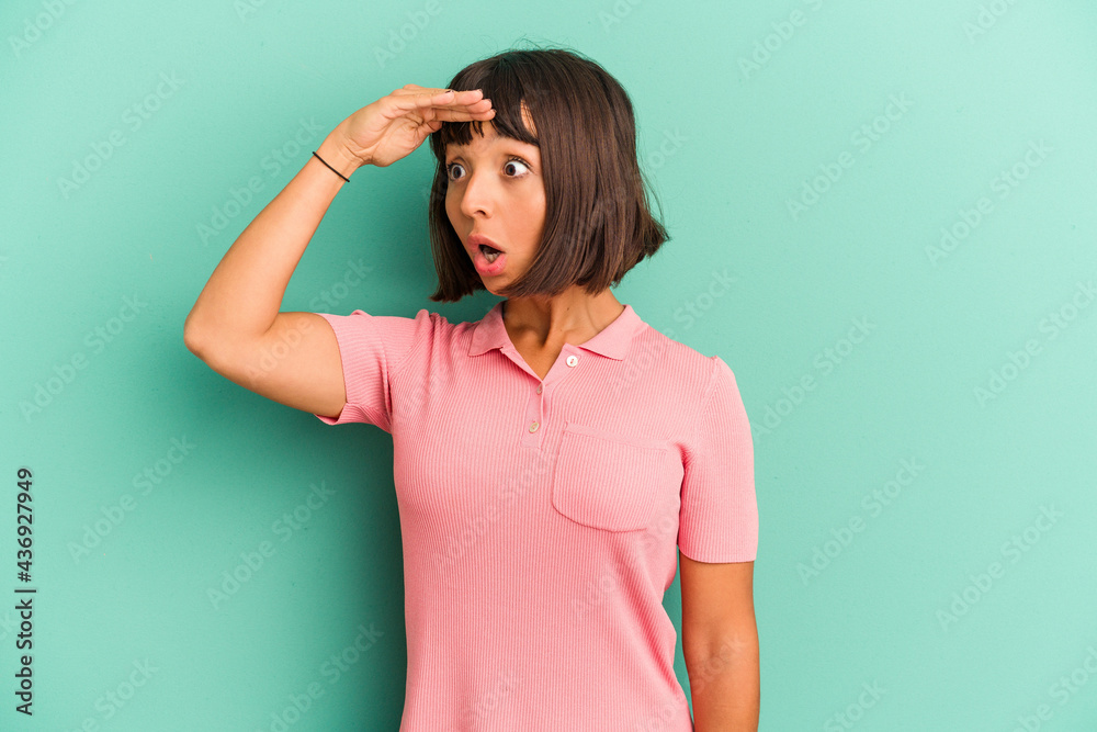 Young mixed race woman isolated on blue background looking far away keeping hand on forehead. Young mixed race woman isolated on blue background looking far away keeping hand on forehead.