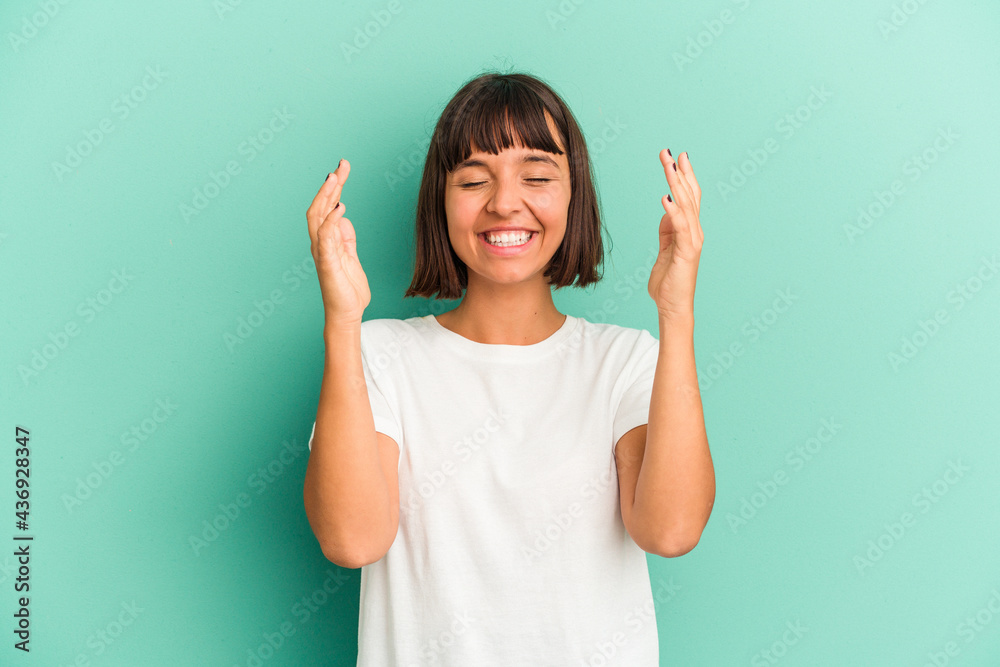 Young mixed race woman isolated on blue background laughing keeping hands on heart, concept of happiness. Young mixed race woman isolated on blue background laughing keeping hands on heart, concept of happiness.