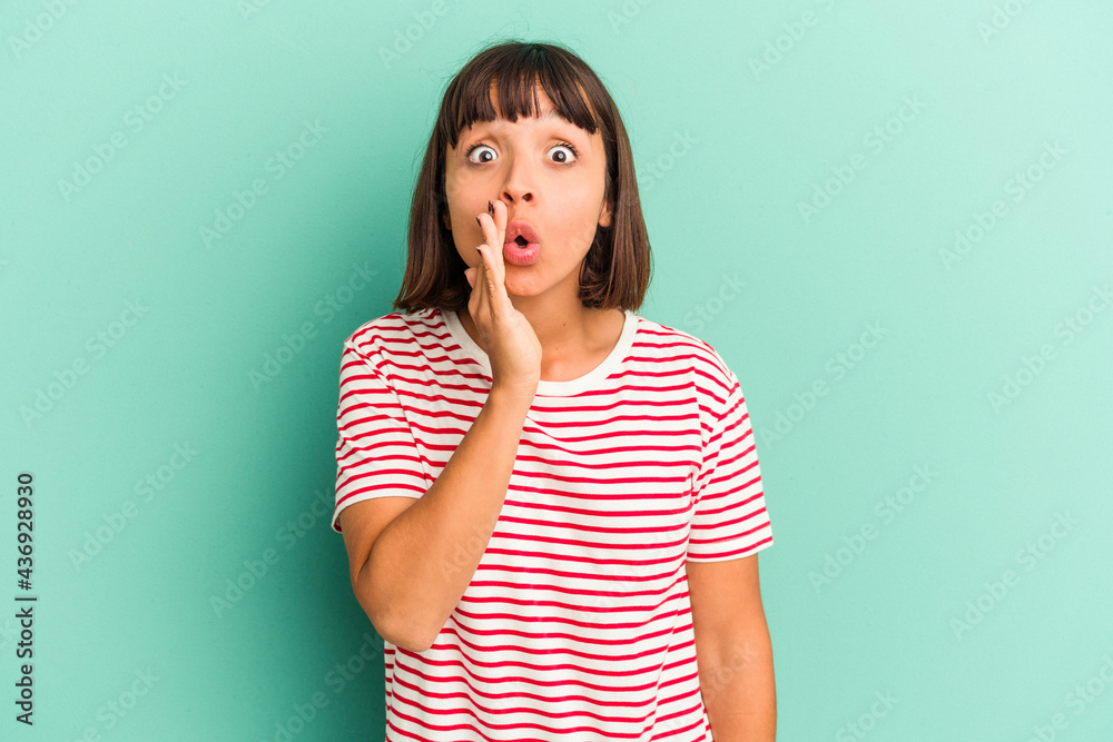 Young mixed race woman isolated on blue background being shocked because of something she has seen. Young mixed race woman isolated on blue background being shocked because of something she has seen.