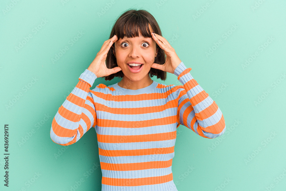 Young mixed race woman isolated on blue background receiving a pleasant surprise, excited and raising hands. Young mixed race woman isolated on blue background receiving a pleasant surprise, excited and raising hands.