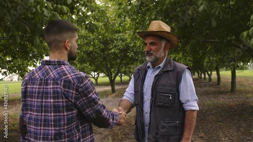 two man handshake in walnut orchard