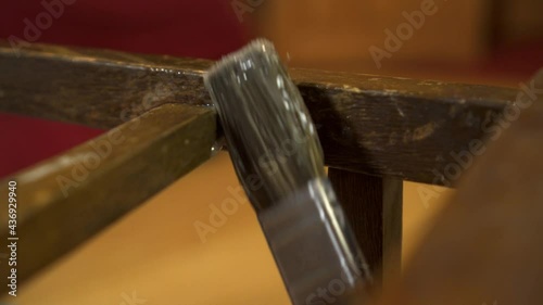 Gluing wood parts in the workshop. Repair and restoration of furniture. Applying glue with a brush on an old wood lacquered chair
