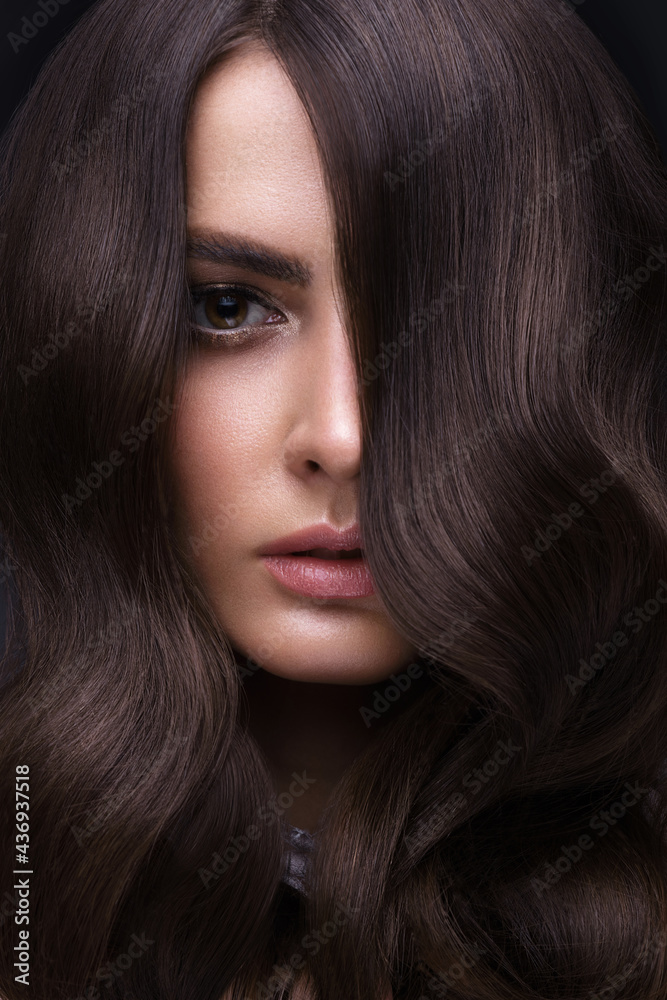 Fototapeta premium Beautiful brown-haired girl with a perfectly curls hair, and classic make-up. Beauty face and hair.