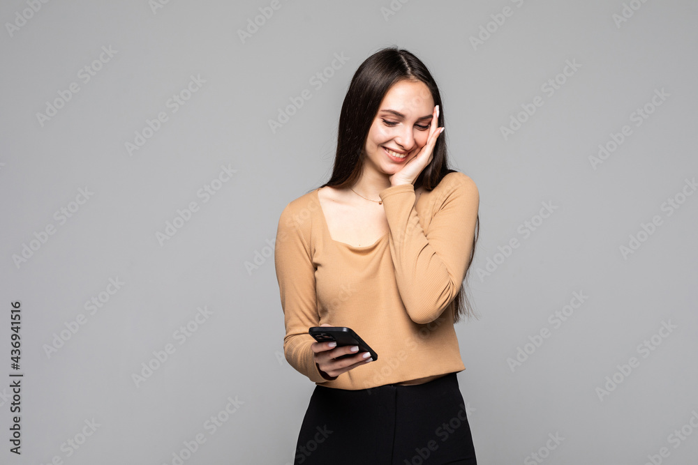 Naklejka premium Portrait of a smiling casual woman holding smartphone remember something over white background