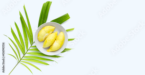 Fresh ripe durian in white plate on tropical palm leaves on white background.
