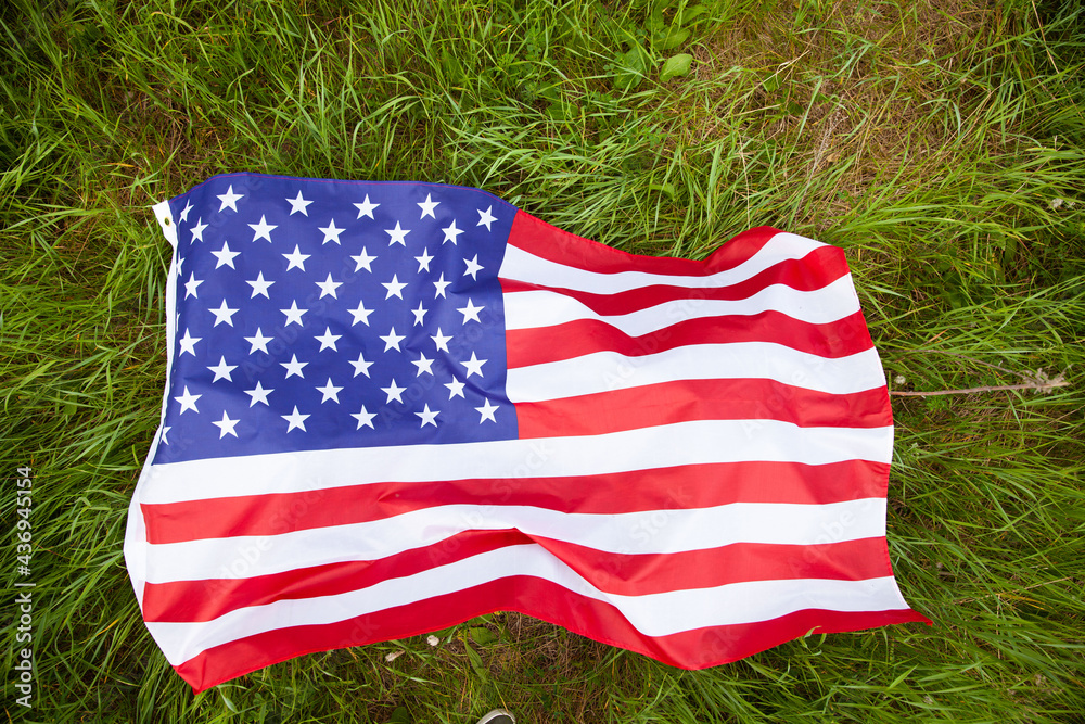 Naklejka premium Close-up of the American flag waving on the green grass. US Flag Day. Independence Day.