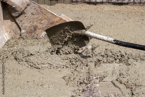 Shovel with cement. The cement is applied with a shovel into the tractor bucket.
