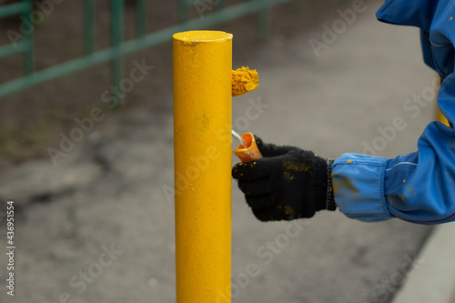 Painting a metal post with yellow paint. Parking bollard painting.