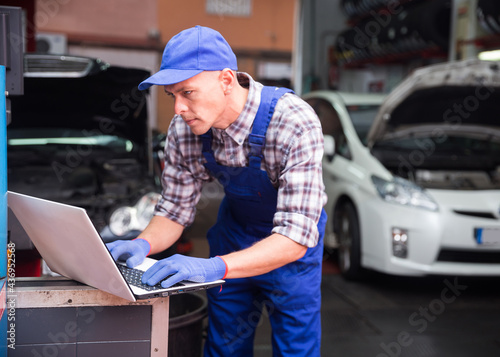 Auto mechanic diagnosing car engine with a laptop with special program at the car repair service center © JackF