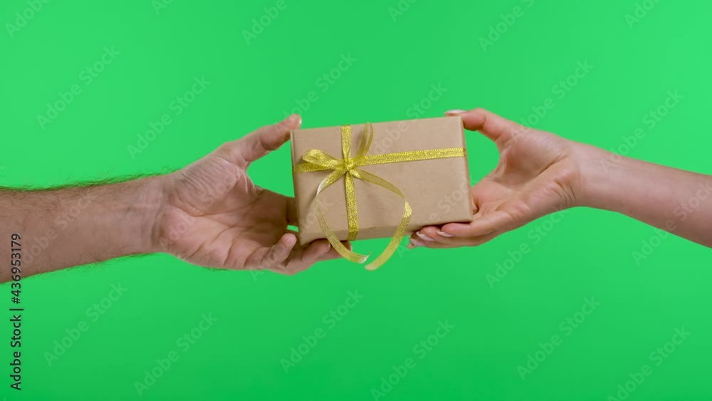 Male hand giving a gift box to a female hand on the background of the green screen of the chroma key. The concept of the holiday, gifts, birthday, Valentine's Day. Slow motion. Close up.