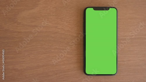 Smartphone place on wood table, Green screen telephone, Close up display mobile phone with mock up, Chroma key monitor, Close-up the cell phone on brown desktop, Mockup smartphone, Slider top view.  