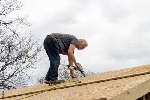 carpenter with nail gun on roof