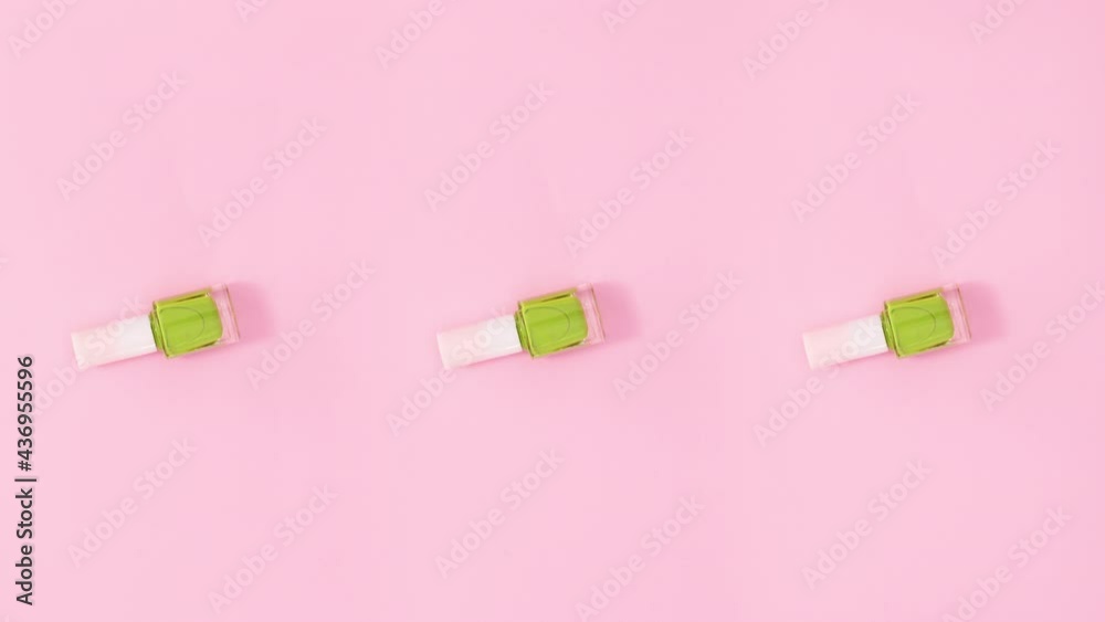 Three nail polishes bottles rotate on pastel pink background. Stop motion Three nail polishes bottles rotate on pastel pink background. Stop motion