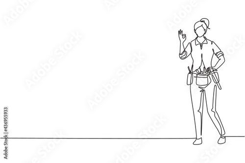 Single continuous line drawing handywoman stands with gesture okay and tools such as pliers, screwdriver, hammer that is placed on his work shirt. One line draw graphic design vector illustration