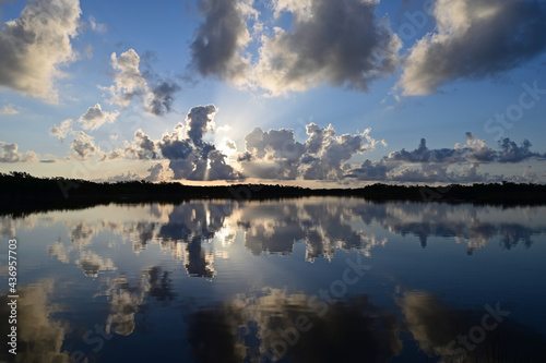Colorful sunrise cloudscape reflected in calm water of Nine Mile Pond in Everglades National Park, Florida in summer.