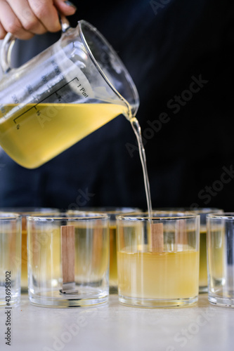 The girl pours wax into glass glasses with wicks.