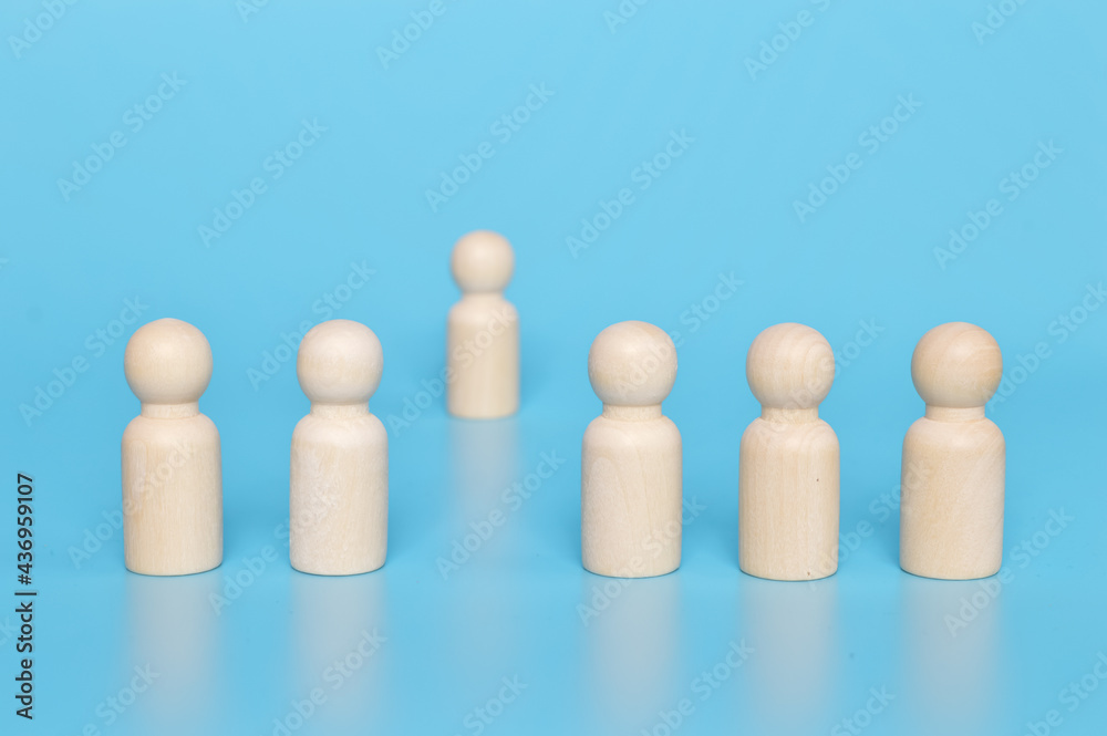 Wooden doll figure standing distantly from the team. Firing someone concept Wooden doll figure standing distantly from the team. Firing someone concept