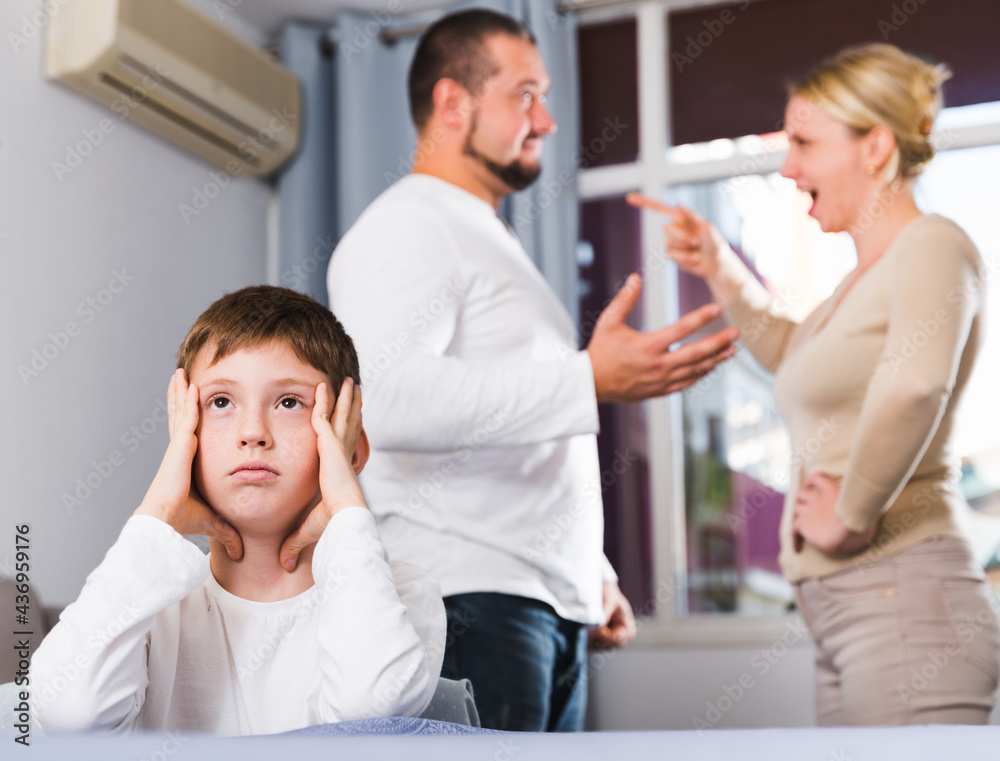 Fototapeta premium Sad desperate little boy during parents quarrel in home interior