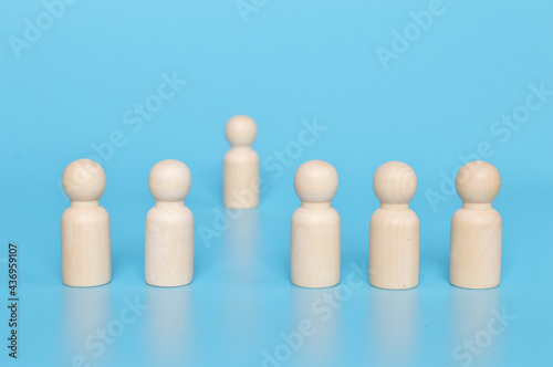 Wooden doll figure standing distantly from the team. Firing someone concept © TeacherPhoto