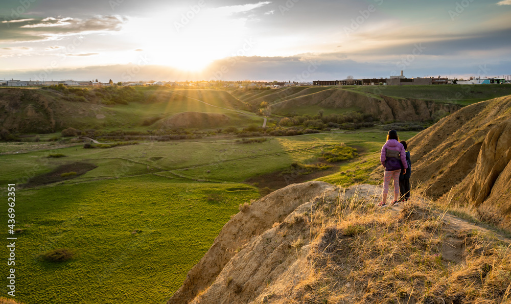 Medicine Hat Alberta Canada, May 14 2021: Two children watch a sunset over Seven Persons Coulee while on vacation in a Canadian City.