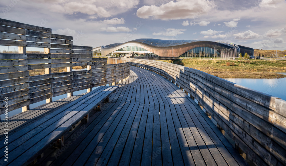 Calgary Alberta Canada, May 12 2021: A wooden boardwalk bridge at the Rocky Ridge YMCA sport facility crosses over a natural habitat area in a Canadian City.