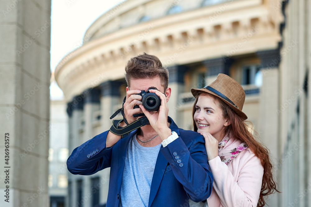 Happy love couple of tourists taking photo on excursion or city tour. Photos on the background of urban architecture