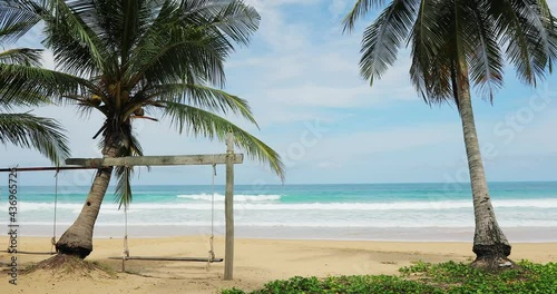 Sea with coconut tree and swings at the beach on a sunny day Summer beach with sunny sky overlooking the horizon and ocean waves in high season Thailand Concept of travel vacation footage background