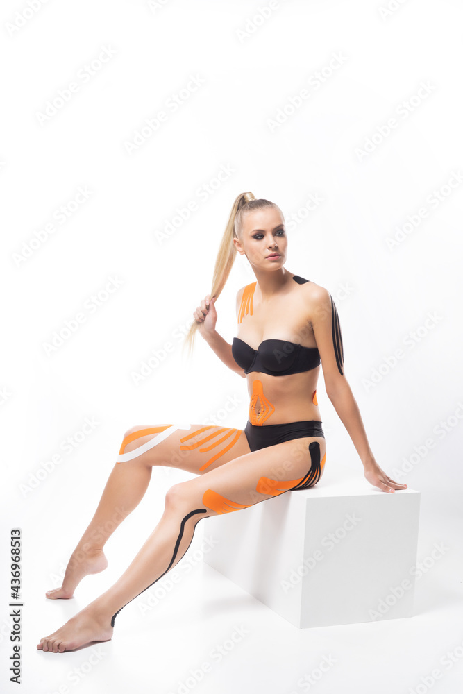 Physio tapes applied to the body of a young athletic woman isolated on white background. Physiotherapy, kinesio taping, kinesiology and recovery treatment. Physio tapes applied to the body of a young athletic woman isolated on white background. Physiotherapy, kinesio taping, kinesiology and recovery treatment.