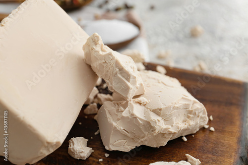 Board with fresh yeast on light background, closeup