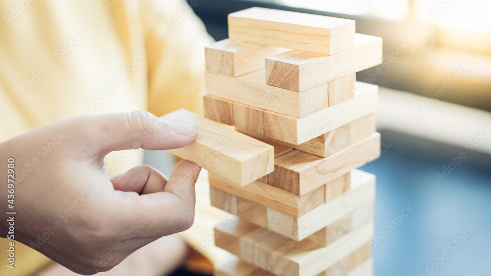 Business growth with wooden blocks concept, Planning to Reduce Investment Risks with Wooden Game Models, hand of a business woman placed a wooden block on a high tower,Management of limited resources. Business growth with wooden blocks concept, Planning to Reduce Investment Risks with Wooden Game Models, hand of a business woman placed a wooden block on a high tower,Management of limited resources.