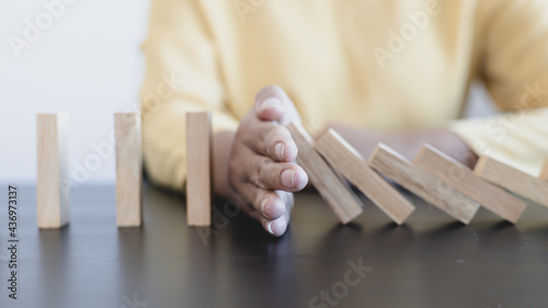Businesswoman stops hands falling over domino to stop risk continuously, Continuous damage reduction, Preventing damages and eliminating risks, End business risks, Stop business domino failures.