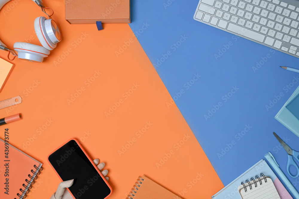 Smart phone, headphone, keyboard and notebook on two tone blue and orange background. Smart phone, headphone, keyboard and notebook on two tone blue and orange background.
